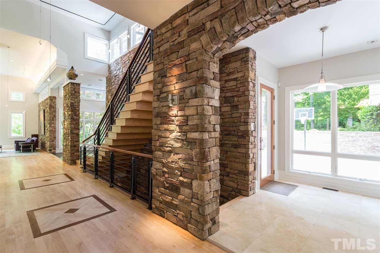 A contemporary floating staircase, with tread boxes wrapped in exquisite white maple, is an architectural wonder and showcases cherry inlay on the landing, contemporary custom iron balusters, and  hardwood handrail as it ascends to the upper-level.