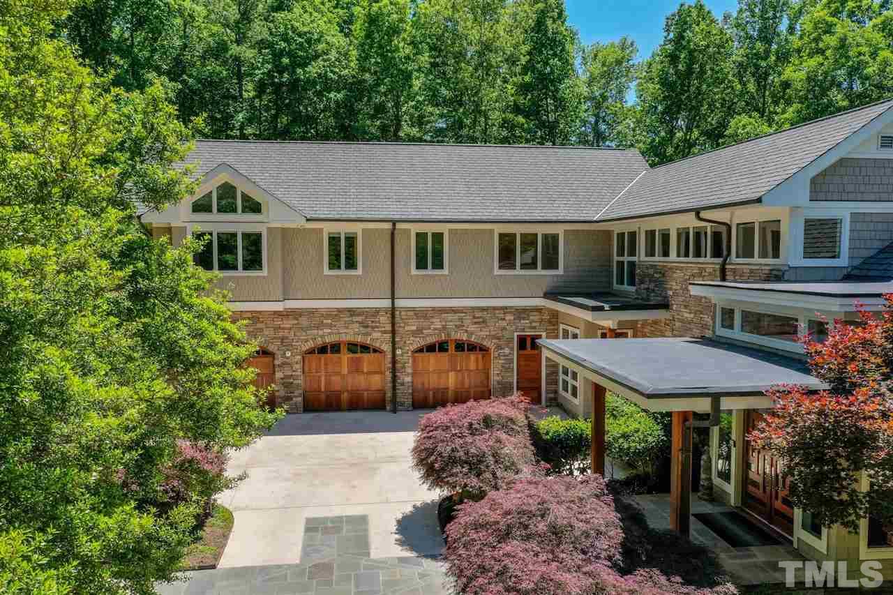 The long driveway leads to an oversized 3-car garage with mahogany & glass doors and 2 Tesla chargers.Up to 4 cars can park on the lower-level parking pad outside the home office and 2 more cars can park on the upper parking pad just below the front door.