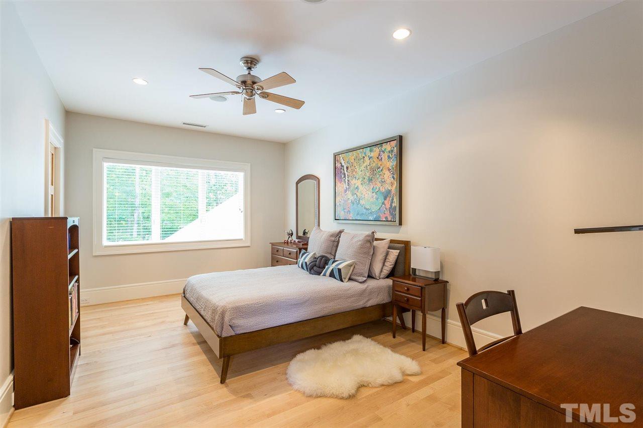 Bedroom Two features a walk in closet with full-length mirror, recessed dimmable lighting, ceiling fan, thermostat, and  triple windows with views of the pool and woods. It shares a 