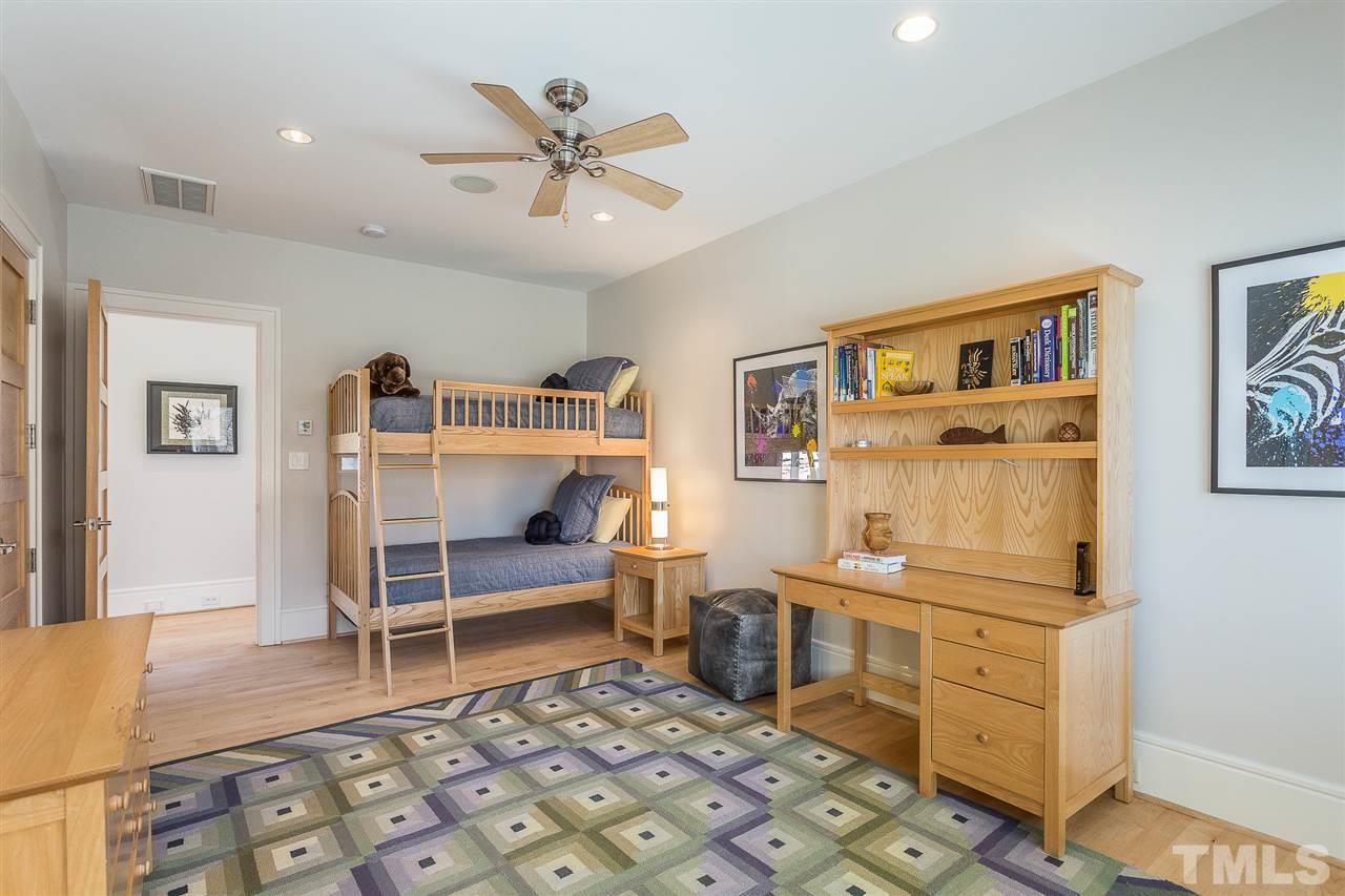 Bedroom Three  is generous in size and features a built-in closet with a full-length mirror, dimmable lighting, ceiling fan, thermostat, and triple windows overlooking the pool and woodlands.