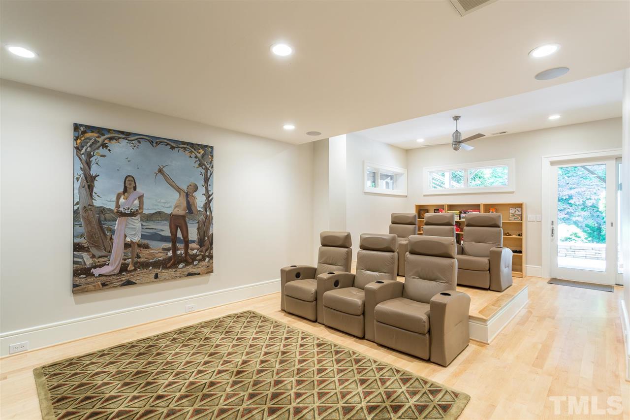 The lower-level media room features surround sound, 6 reclining theater chairs(3 on a raised platform, and a sliding glass door to the patio. The back of the room has a reading nook and play area.
