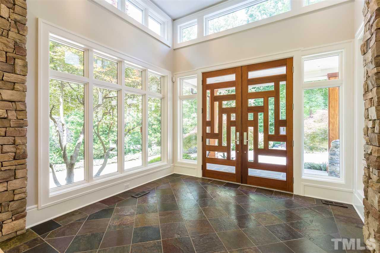 Contemporary custom-built Santos mahogany and glass double doors with an intricate modern design welcome you to the impressive foyer that is graced with the warmth and natural beauty of Indian multi-color slate flooring.
