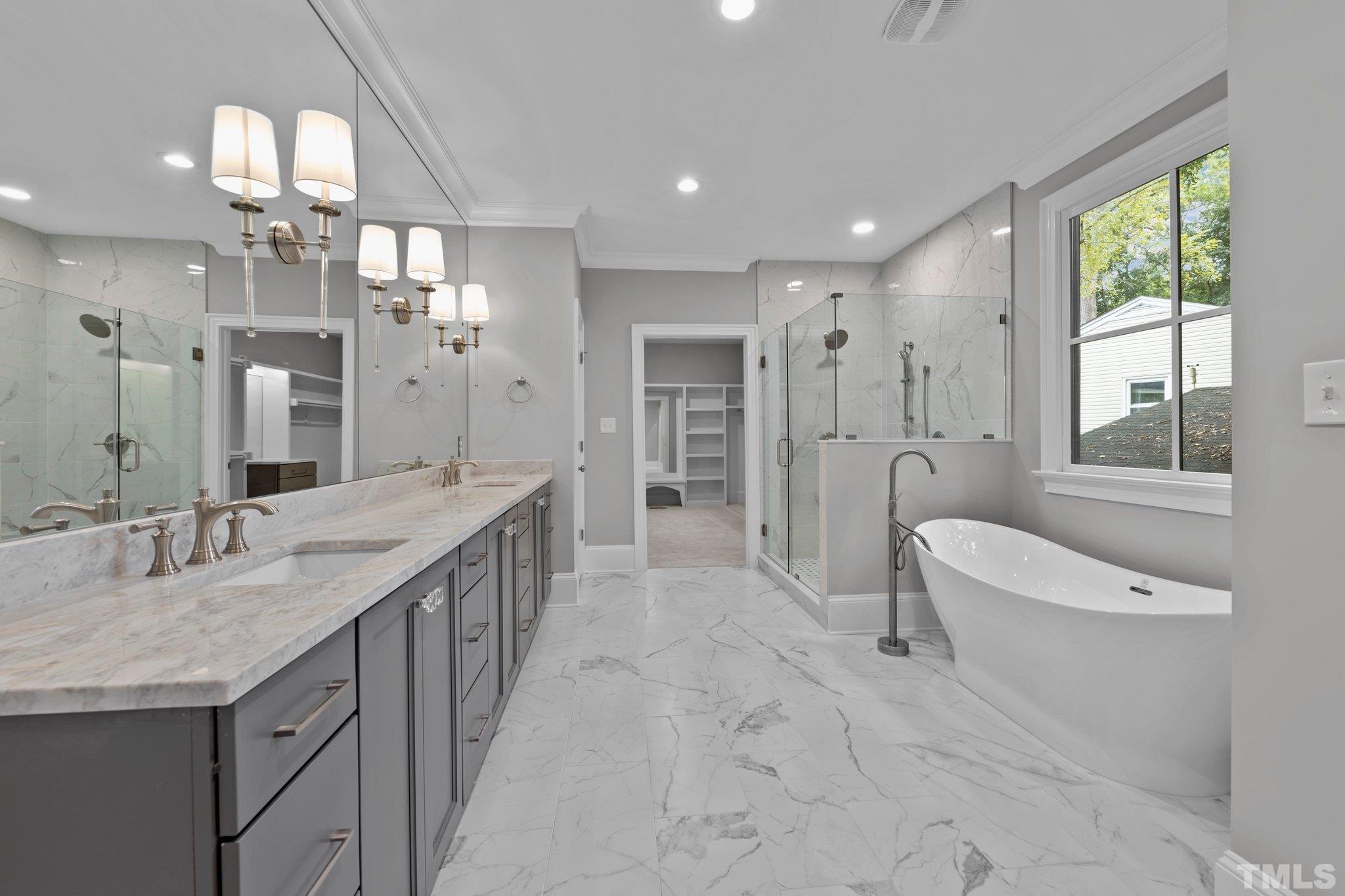 Luxurious master bathroom spa featuring dual vanities with quartzite counter top, large garden tub, walk-in shower with marbled tiling to the ceiling and porcelain floor tiles.