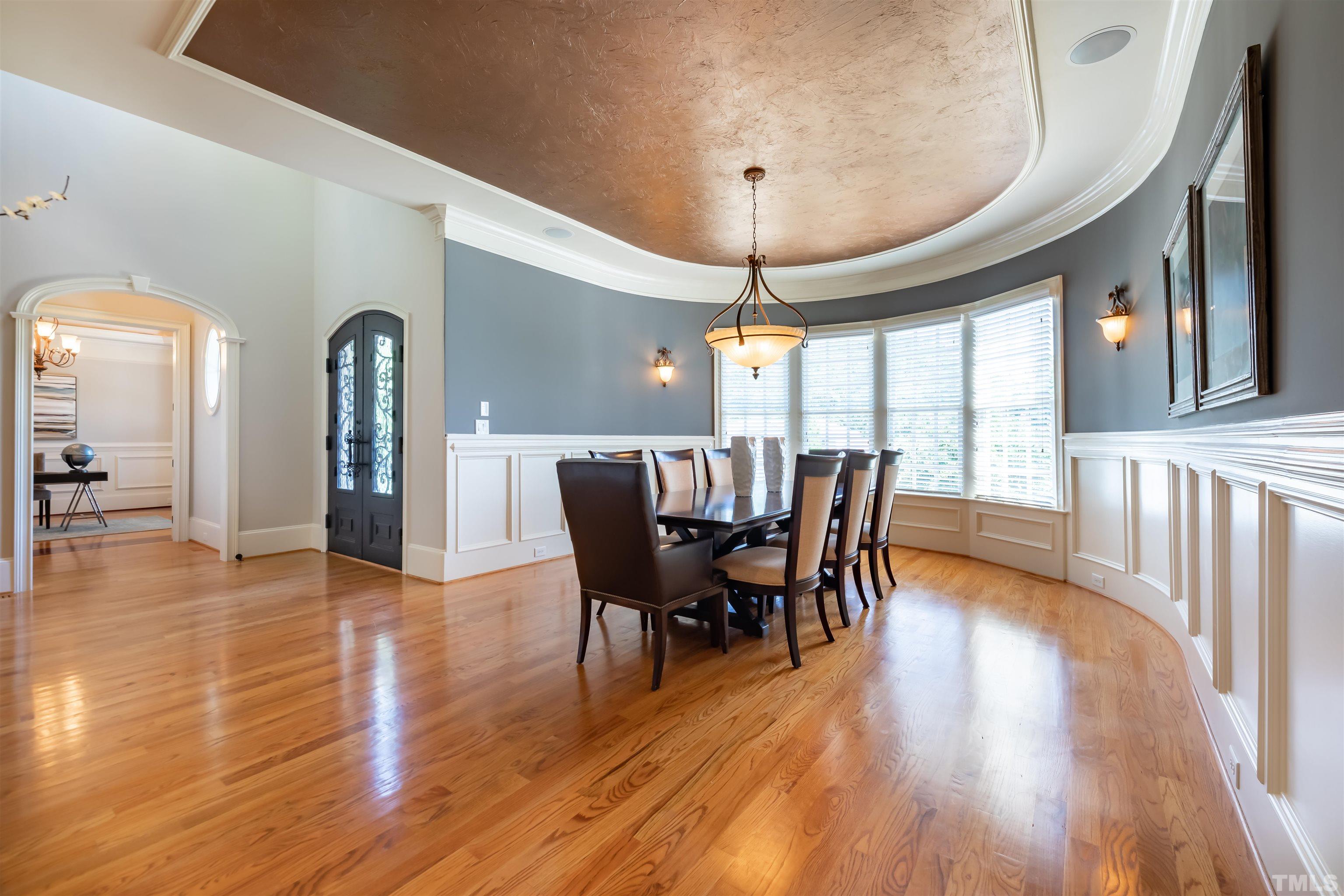 To the left of the foyer is the banquet sized dining room, perfect for large dinner parties.  As you can see, the ceiling trim follows the curved wall.  Lots of windows for natural light.  Wainscoting defines the walls.