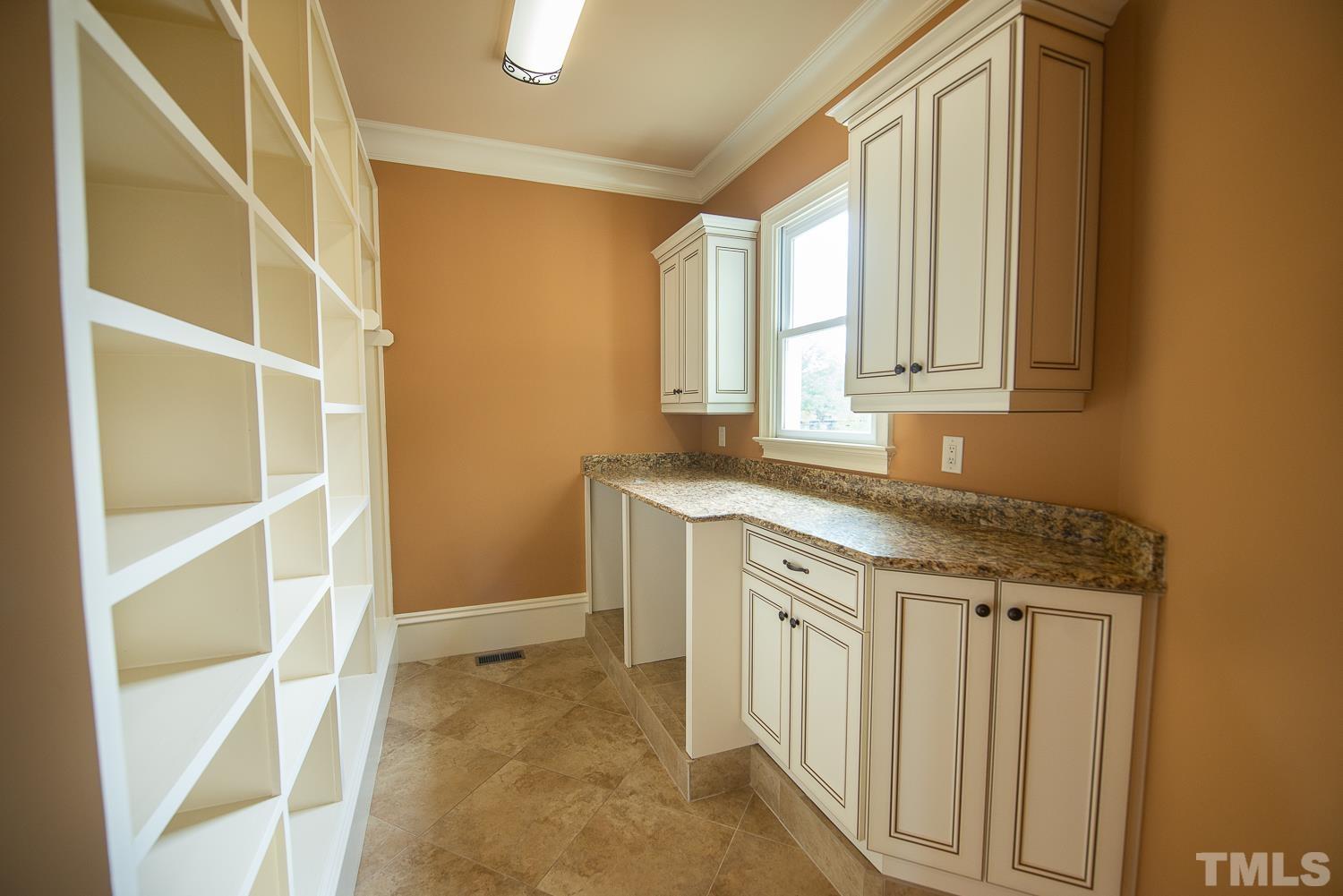 There are two laundry rooms. This one is located on the first floor. It has lots of cabinets and granite  counter tops and upgraded ogee edge. There is a wall of wood-shelving for food storage.