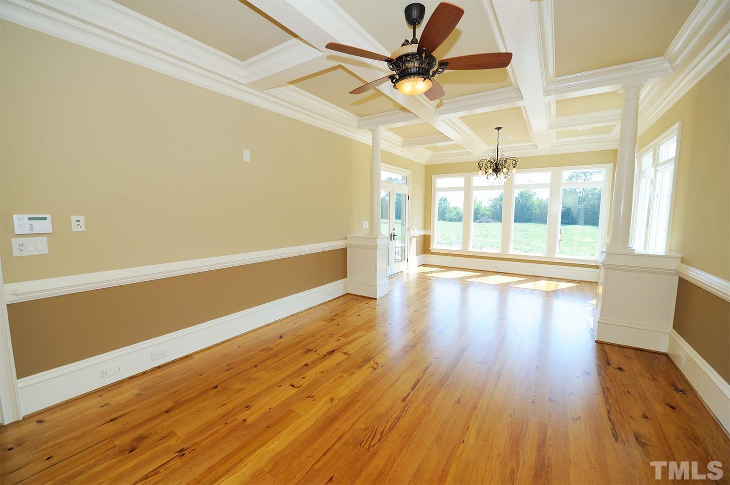 The master suite has a coffered ceiling, chair rail, crown and hardwood flooring. Columns separate it from the sitting room. It has is a door to the covered porch. This room is also on its own zone.