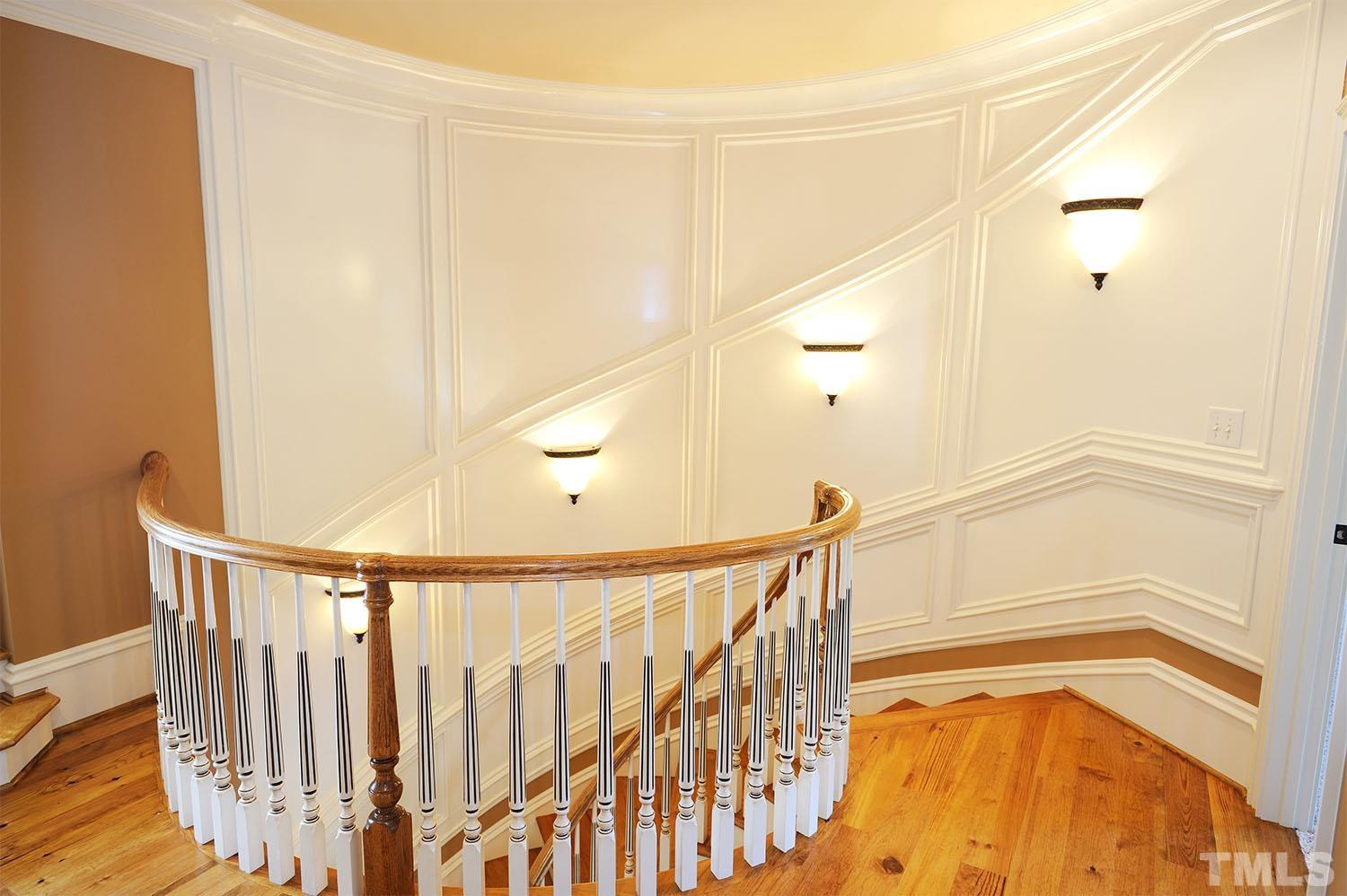 Custom-built curved staircase with hardwoods and gorgeous wall of elegant moldings all the way up the wall. Hardwoods on 2nd floor hallway.