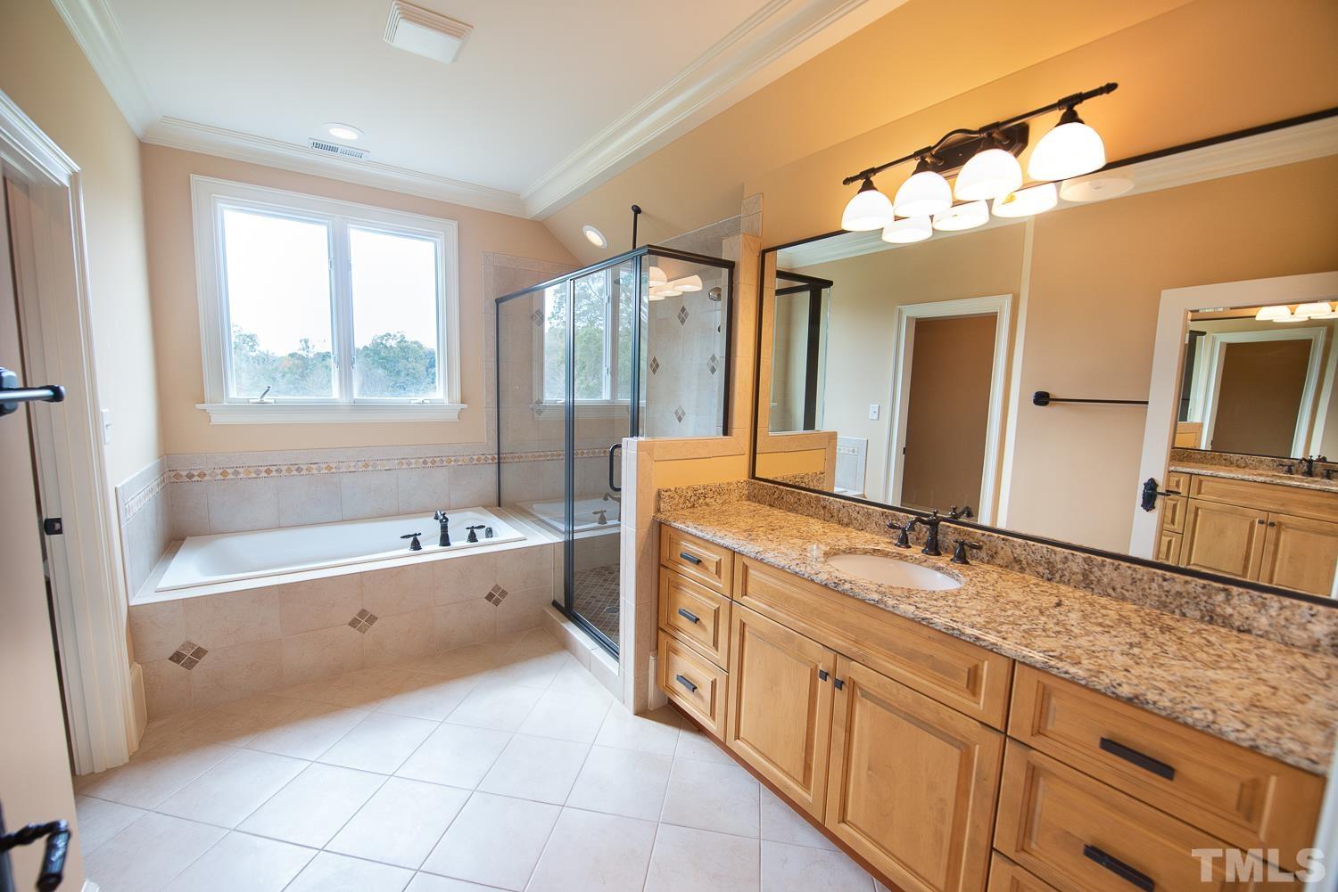 Has large granite vanity with upgraded ogee edge, separate tiled shower with rain shower head, tub and tiled flooring.