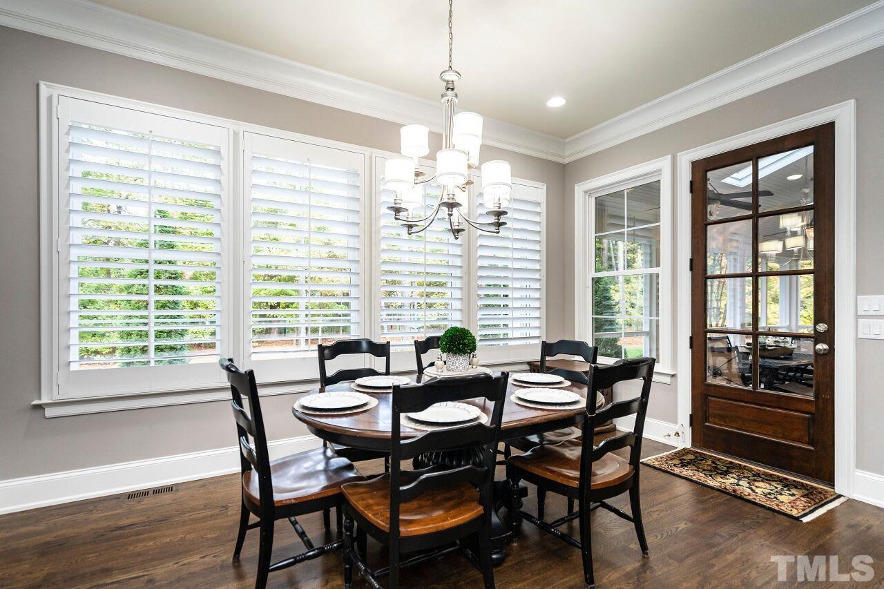 Breakfast Room with 10' ceilings, two piece crown, wood/glass panel access door to screen porch, plantation shutters and hardwood floors.