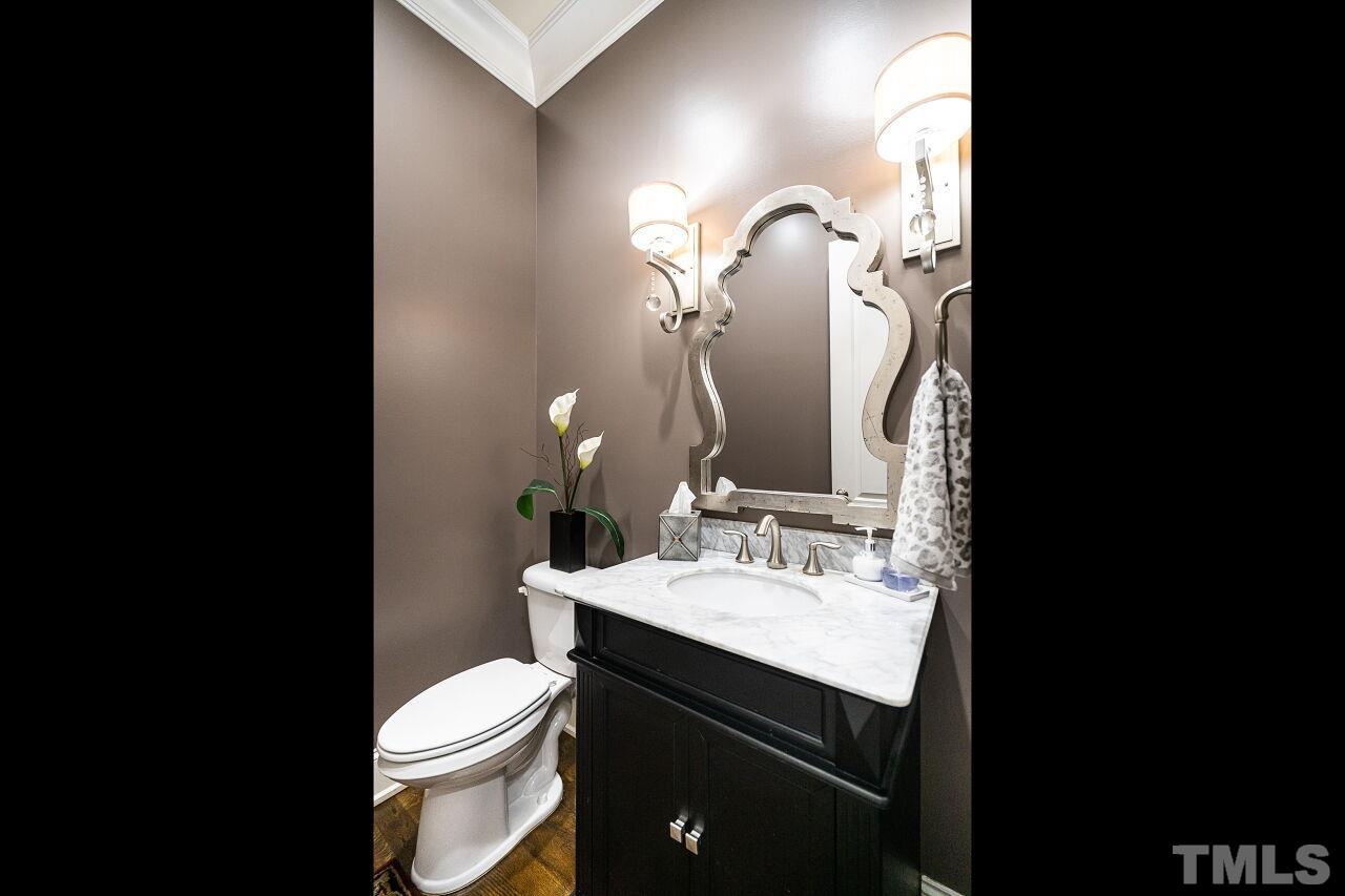 Half-Bath with raised vanity, marble top, custom mirror and hardwood floors.