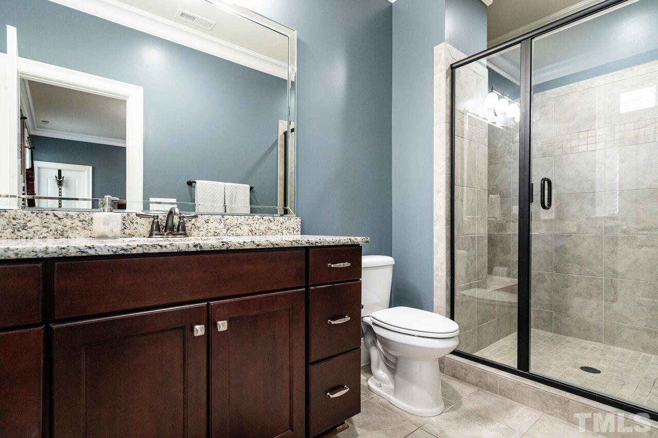 Private Bathroom with raised stained vanity, granite tops, shower with glass door and tile floors.