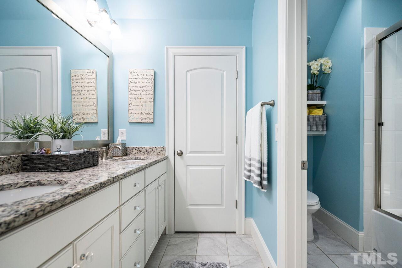 Bathroom with raised painted double vanities, granite top, tub/shower with glass door and tile floors.