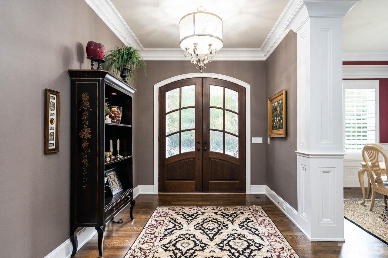 Elegant wide entry foyer with 10' ceilings, two piece crown, solid wood arched double front doors with glass and hardwood floors.