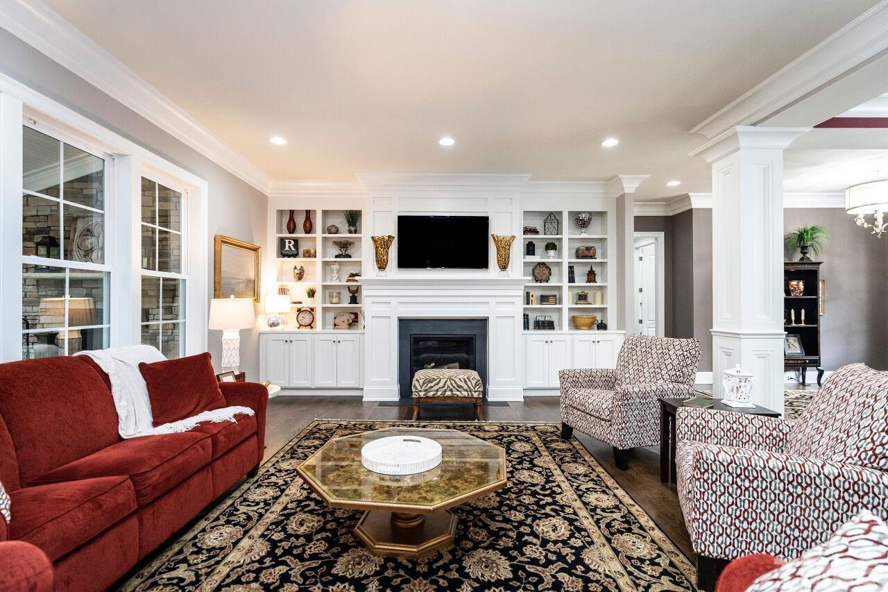 Family Room with 10' ceilings, two piece crown, gas log fireplace, bookcases/shelves, columns, direct lighting, ceiling speakers and hardwood floors.