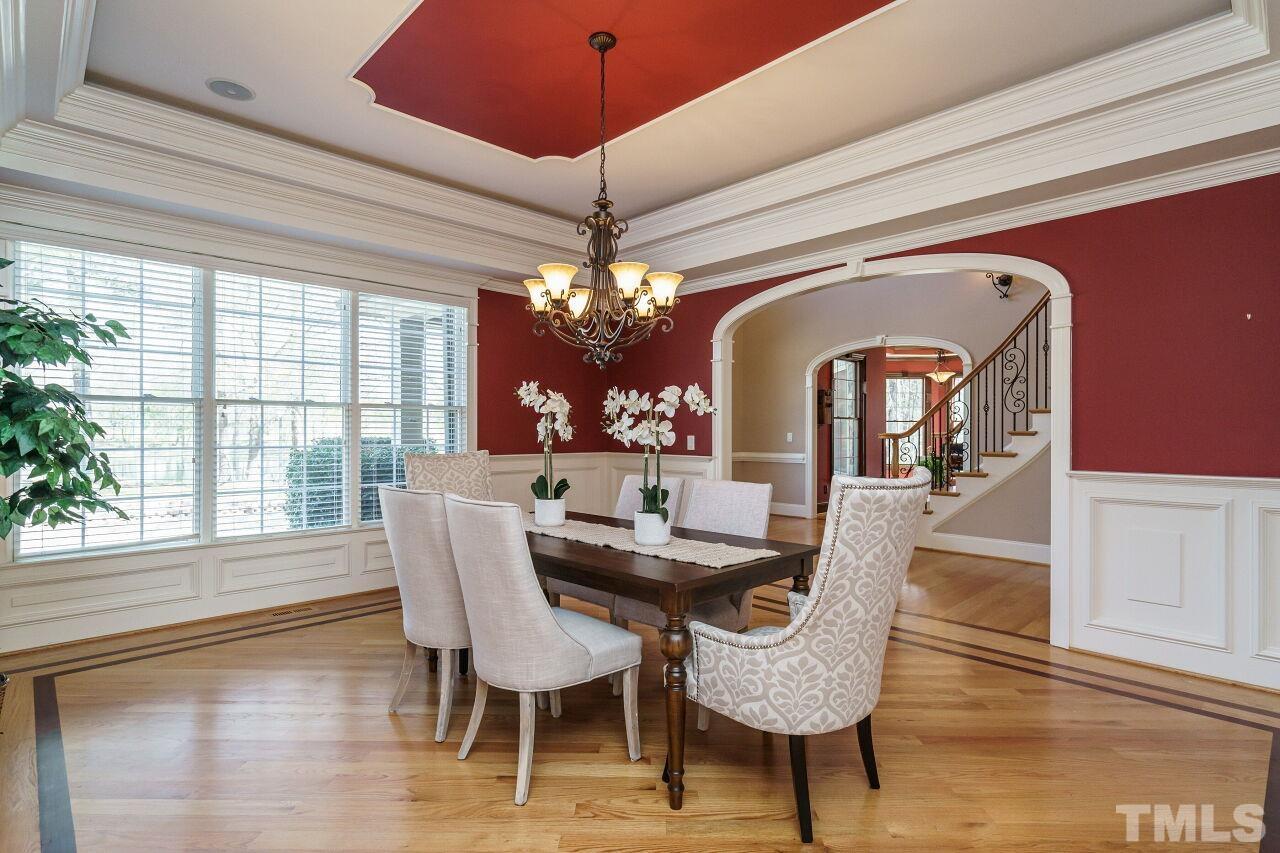 The formal dining room has wainscoting and a trey ceiling, along with glistening hardwood floors.