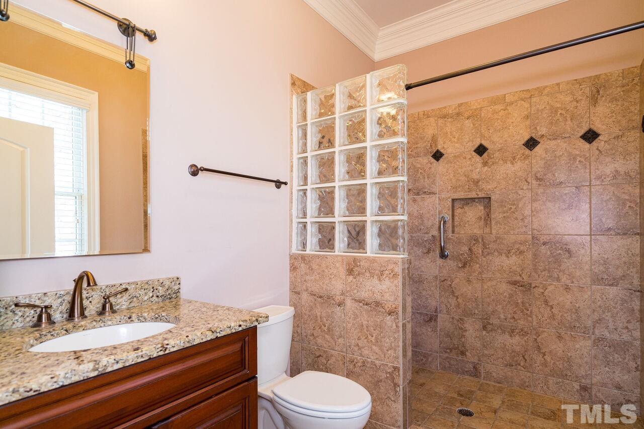Custom tile work adorns the walk-in shower and granite counters adorn the vanity.