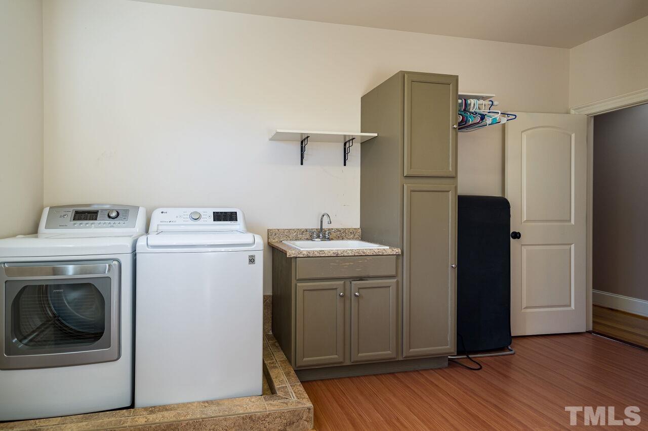 The laundry room has a built-in sink and other cabinetry along with hanging space.