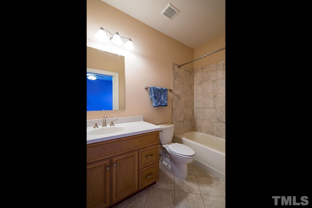 This bathroom has a tub/shower combination with tile surround.