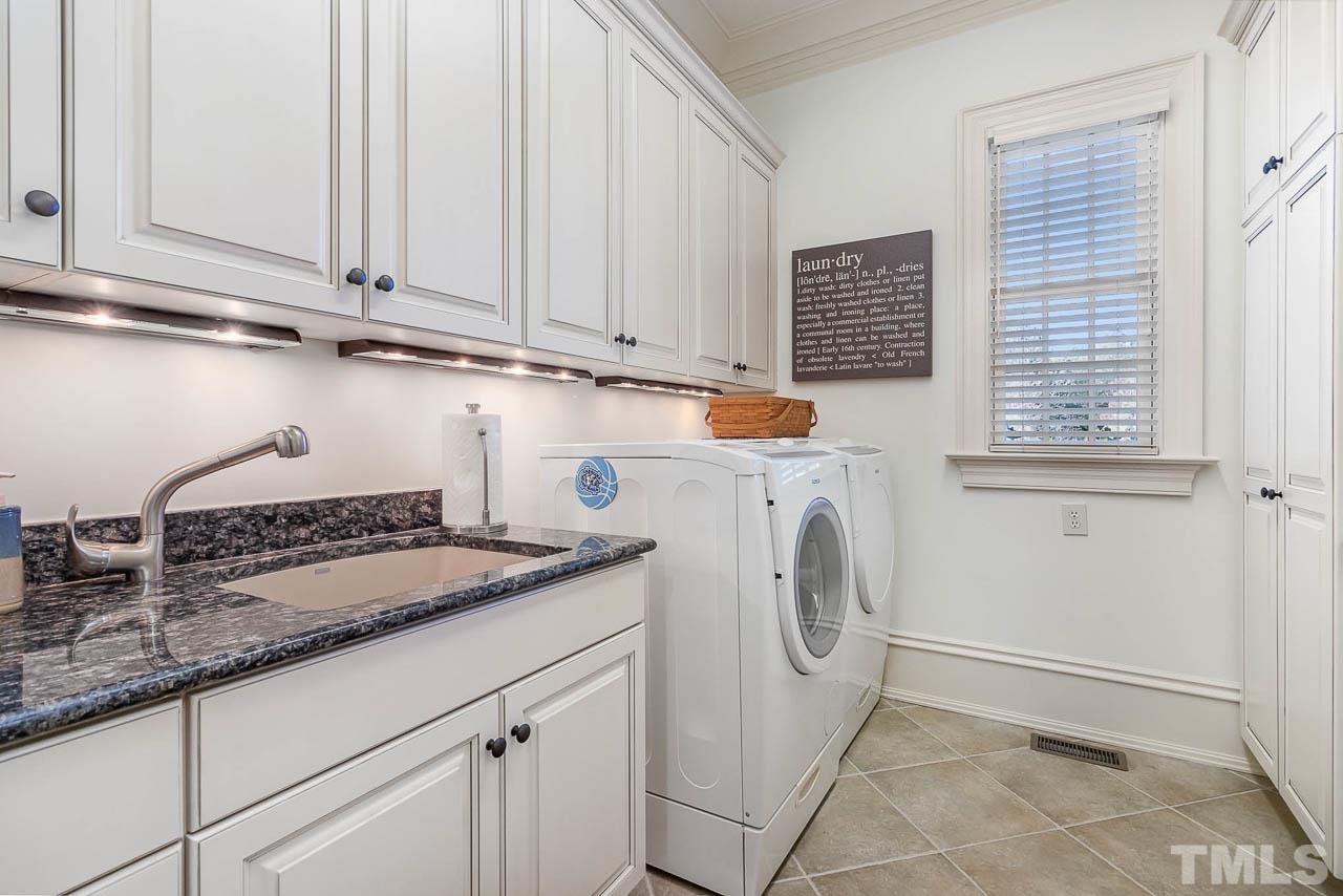 Laundry room has an oversized sink as well cabinets of various sizes to suit anyone's storage needs.