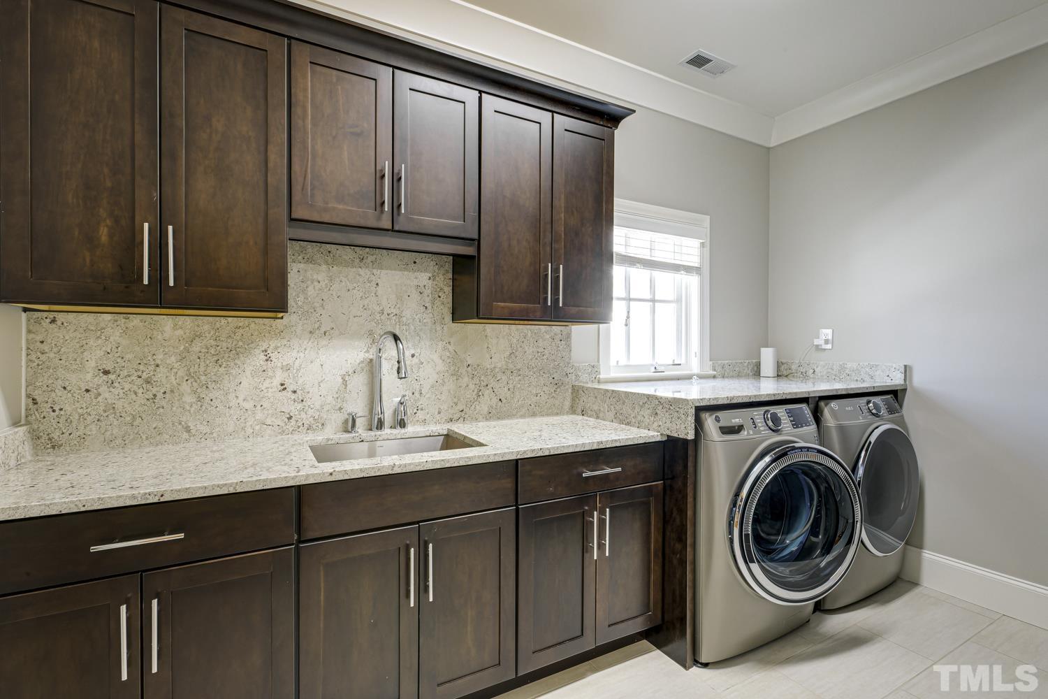 The laundry room is equipped with gorgeous custom cabinets (along the wall across from the washer/dryer-not shown in photo) as well as all of these cabinets and extra storage space.  There's a sink too!