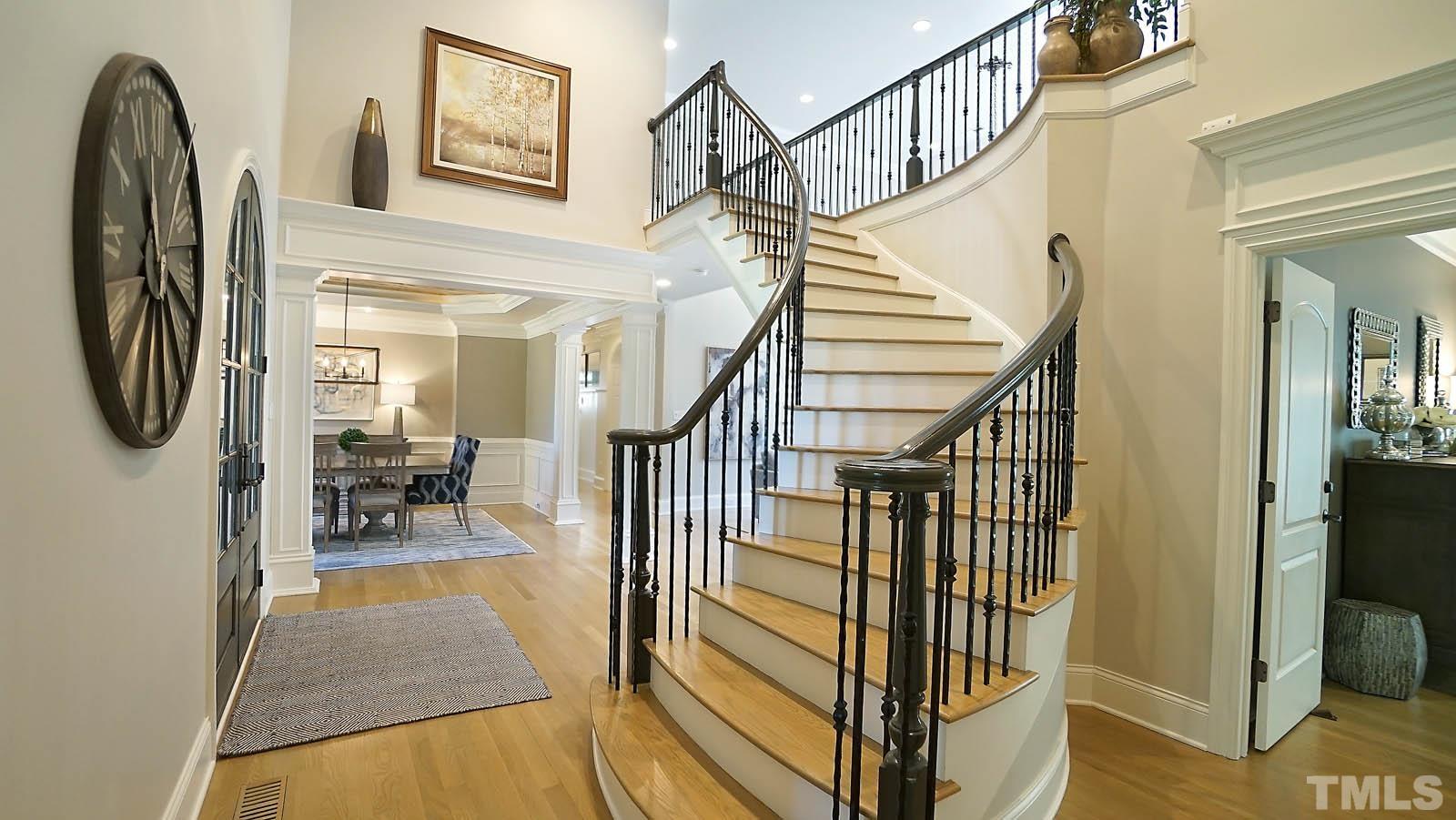 Gorgeous curved staircase with iron balusters and catwalk overlooking family room