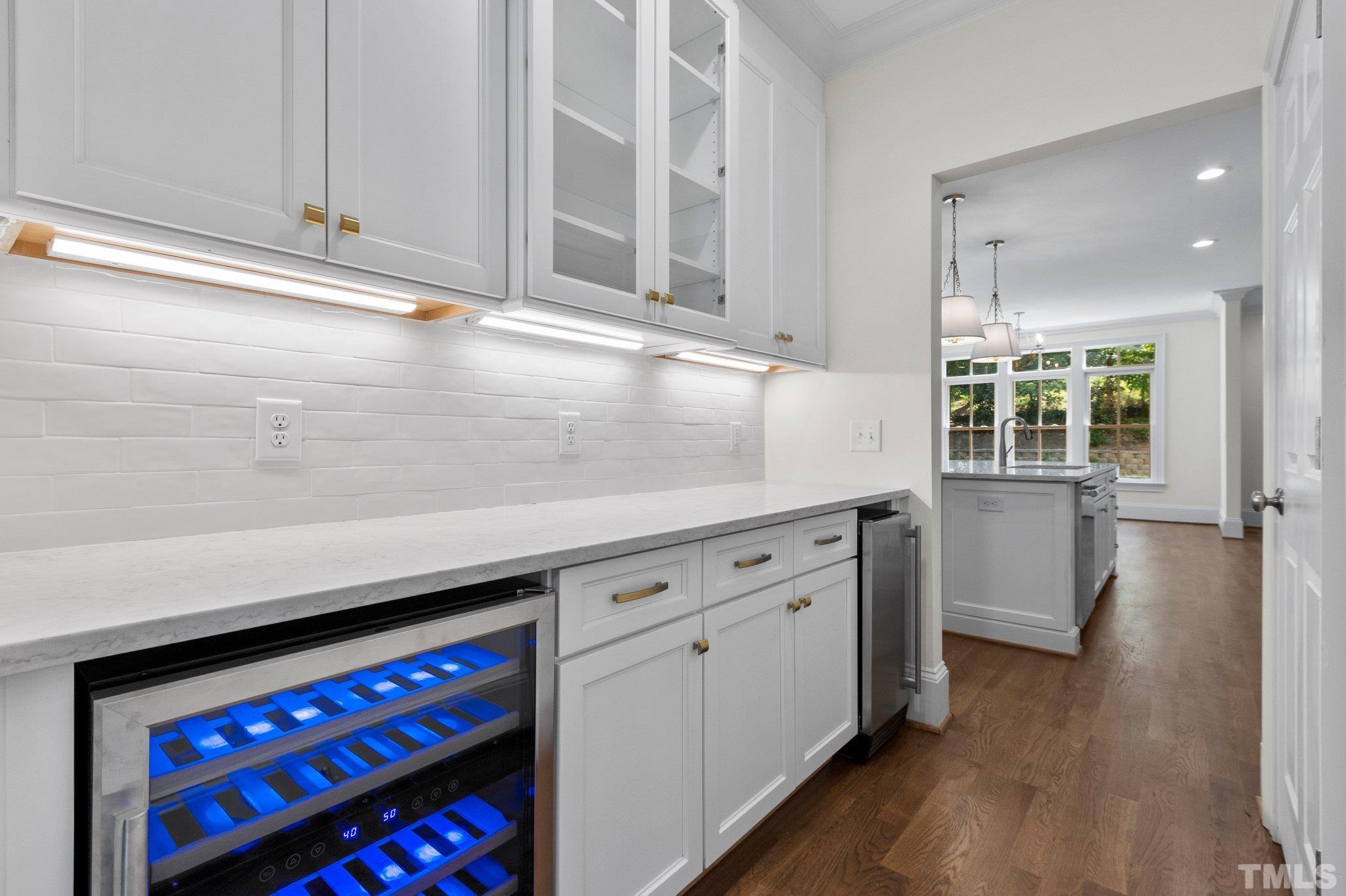 Convenient Butler's Pantry off of kitchen and leading to the dining room. Featuring quartzite countertops, tiled, backsplash, custom cabinetry, beverage cooler, ice maker and access to storage pantry.