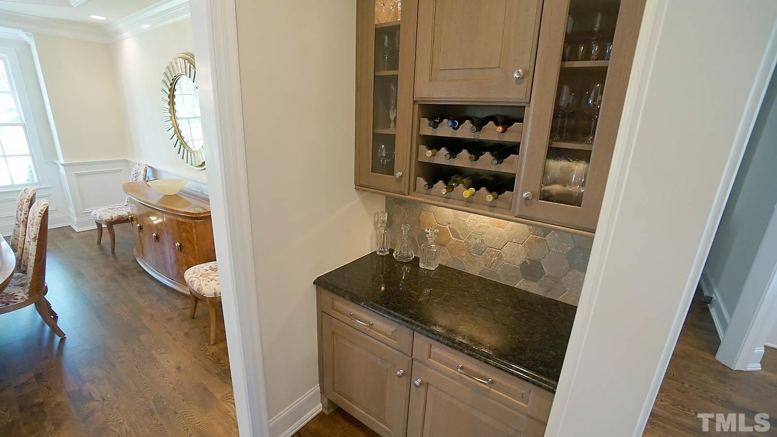 Butler's pantry with beverage fridge, granite counter and tile backsplash.