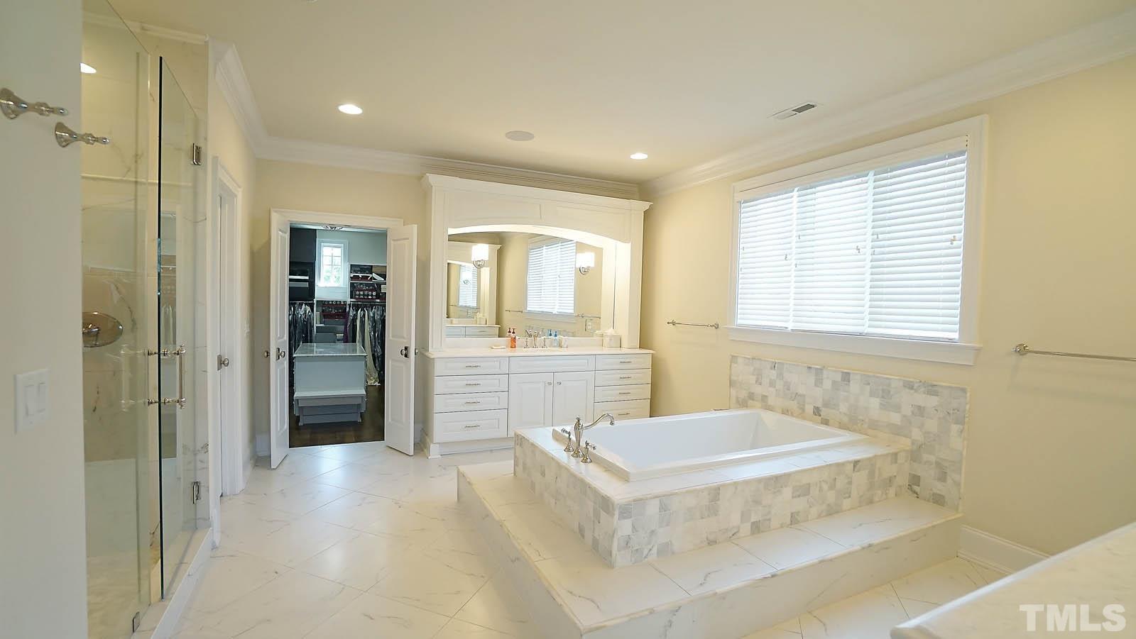 Dual vanities, tiled walk-in-shower and drop tub.