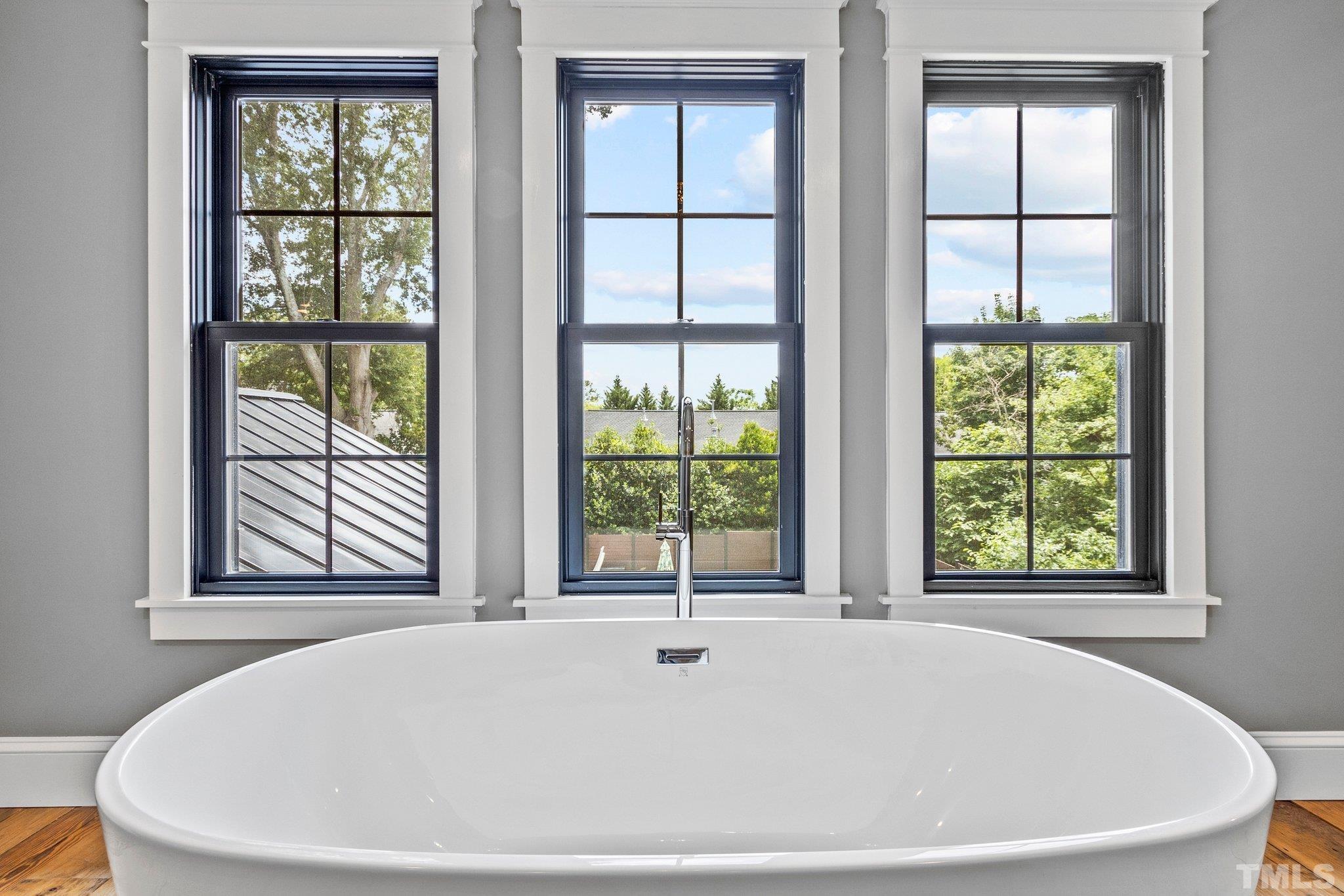 Free-standing soaker tub, flooded with natural light and green tree-top views.