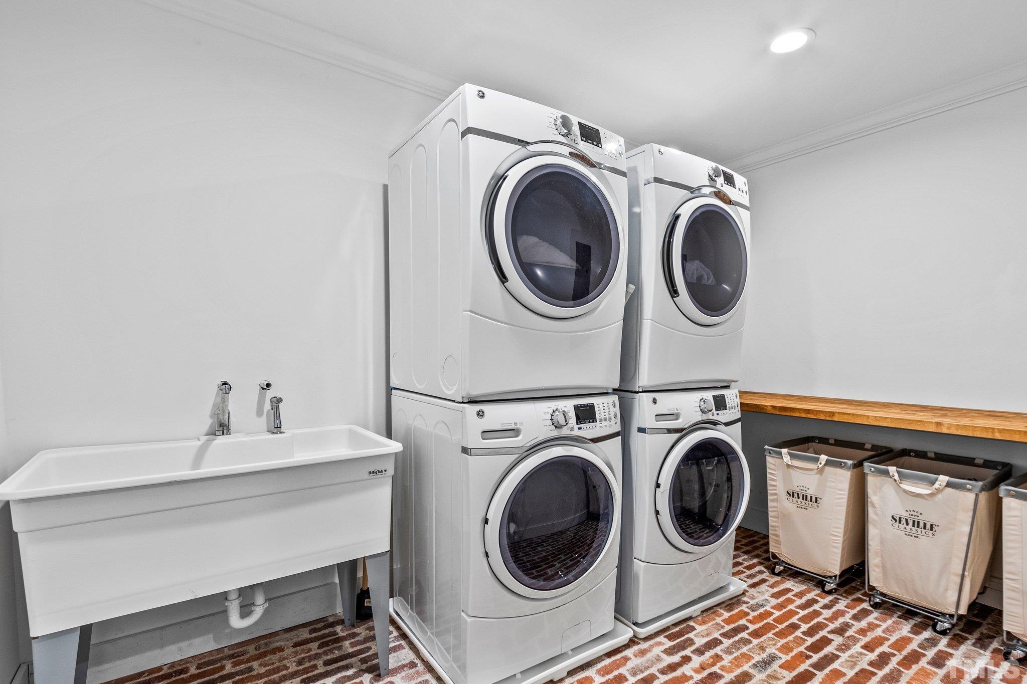 Ample space provided in laundry room, enough to allow for multiple Washer/Dryer sets, a utility sink and folding table.