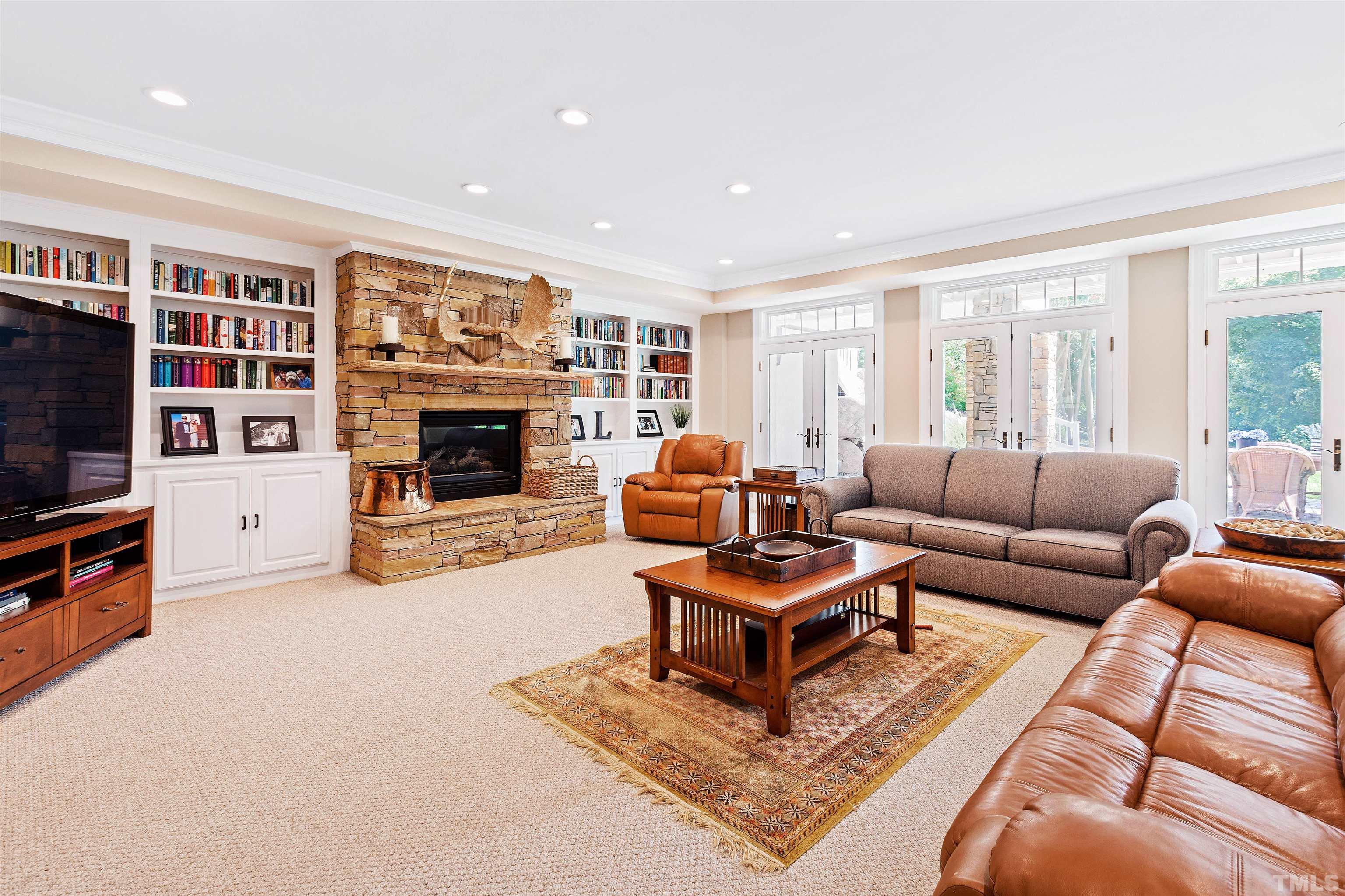 Fully carpeted, features bookshelves, stone fireplace, access to lower patio.